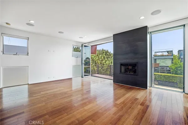 an empty room with wooden floor fireplace and windows