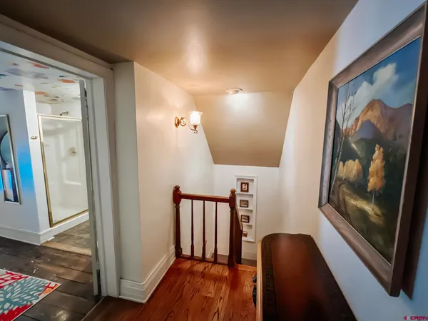 a view of a hallway with wooden floor and stairs