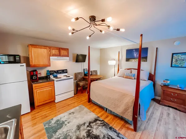 a bedroom with a bed dresser and wooden floor