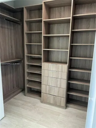 an empty room with wooden floor and a kitchen view