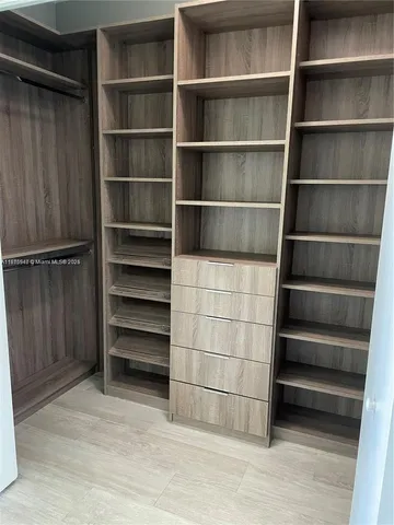 an empty room with wooden floor and a kitchen view