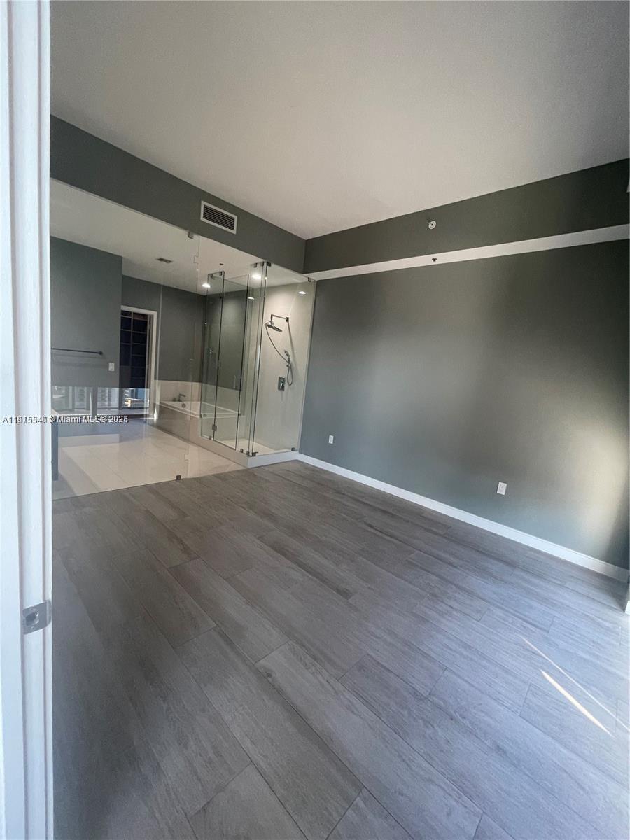 55 Southwest 9th Street, Unit 4304 Miami, FL 33130 - Photo 17 of 32 an empty room with wooden floor and a kitchen view