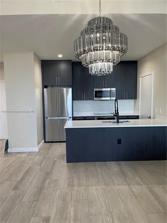 a kitchen with stainless steel appliances a refrigerator and a chandelier