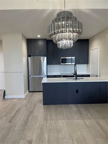 a kitchen with stainless steel appliances a refrigerator and a chandelier