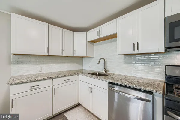 a kitchen with granite countertop white cabinets and white appliances