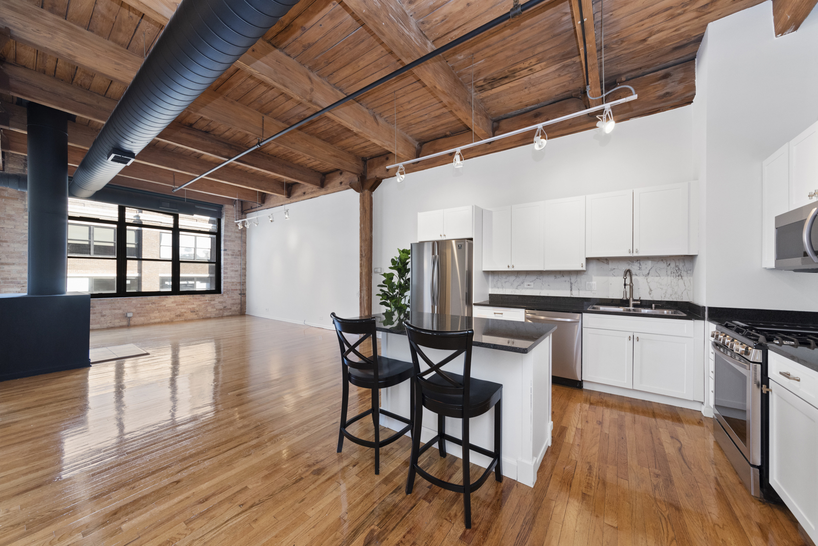 1017 West Washington Boulevard, Unit 5B Chicago, IL 60607 - Photo 4 of 13 a kitchen with stainless steel appliances granite countertop wooden floors stove top oven and cabinets