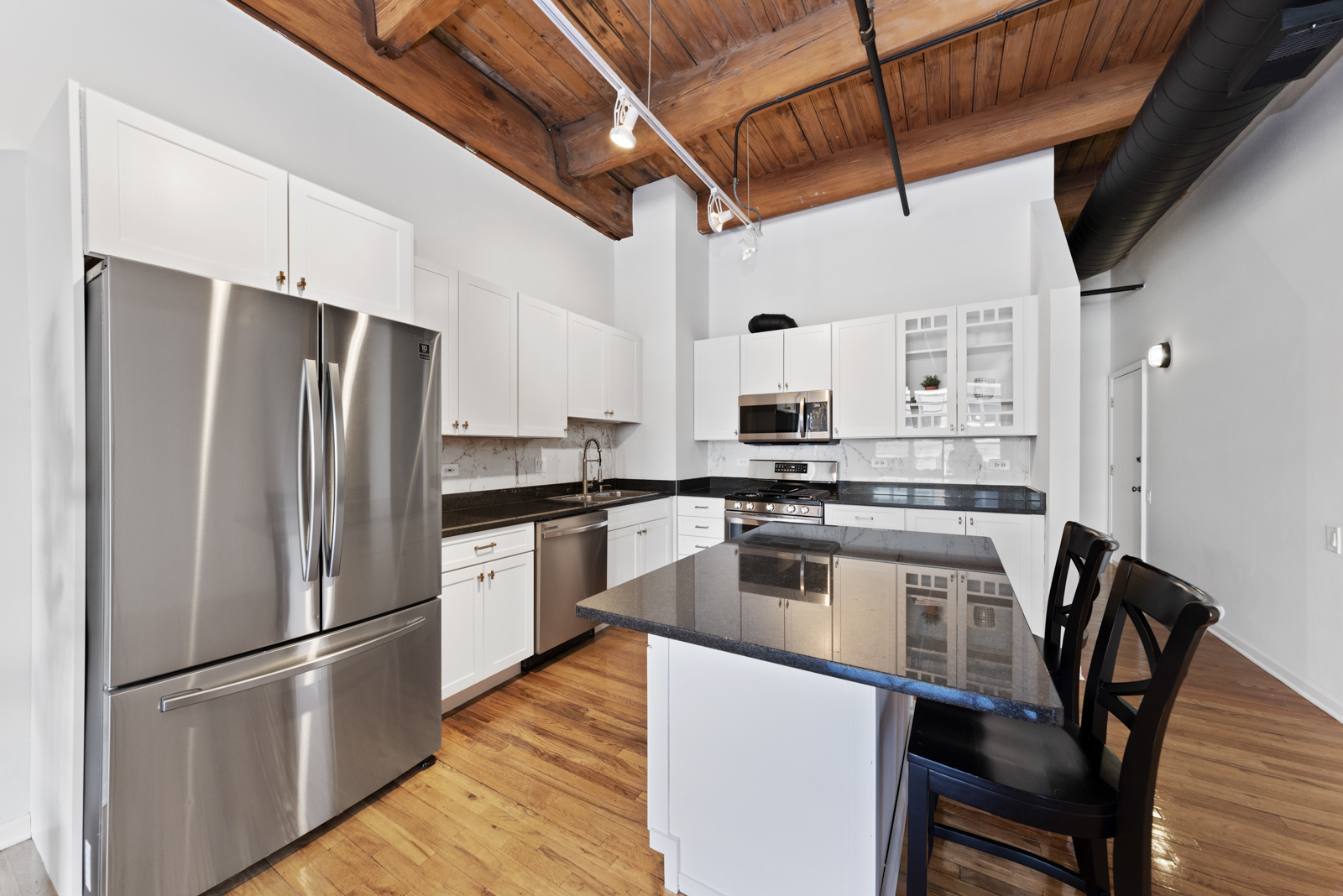 1017 West Washington Boulevard, Unit 5B Chicago, IL 60607 - Photo 5 of 13 a kitchen with stainless steel appliances a refrigerator a stove a sink and chairs
