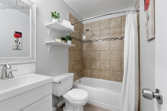 757 Alexander Road, Unit C Colorado Springs, CO 80909 - Photo 12 of 29 Full bathroom featuring wood-type flooring, shower / bath combo with shower curtain, vanity, and toilet