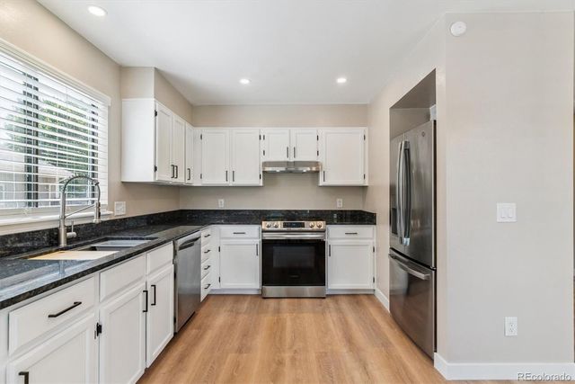 a kitchen with granite countertop a sink stove and refrigerator