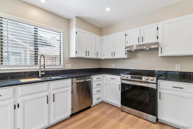 a kitchen with granite countertop white cabinets and a stove