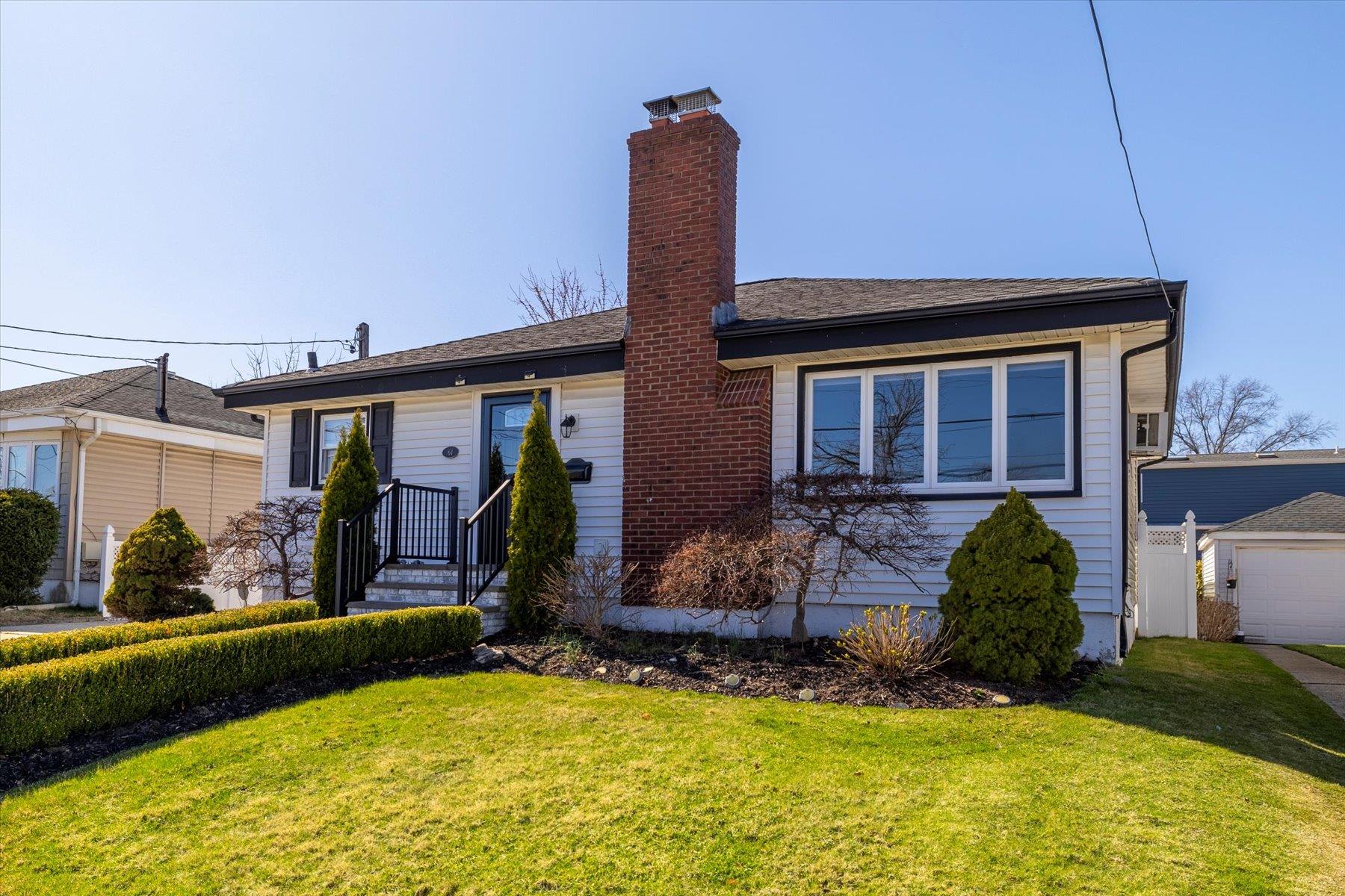 View of front facade with a chimney and a front lawn