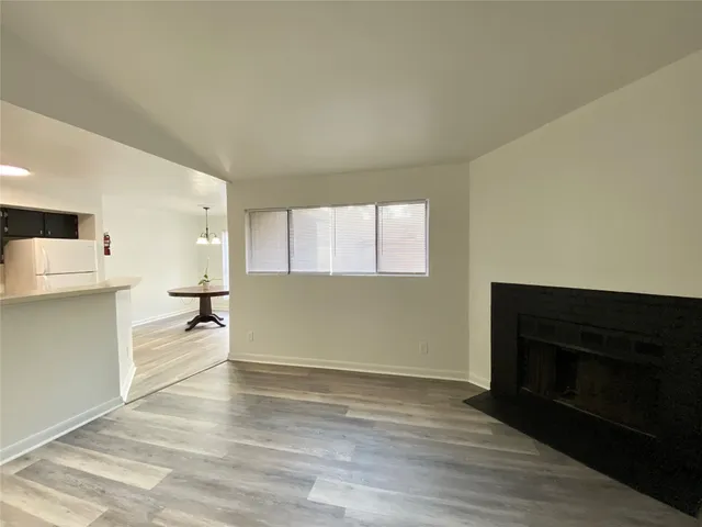 a view of a kitchen and an empty room with a fireplace