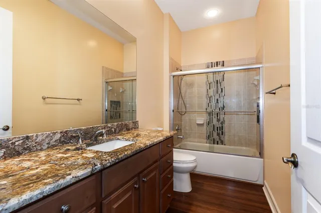 a bathroom with a granite countertop sink toilet and shower