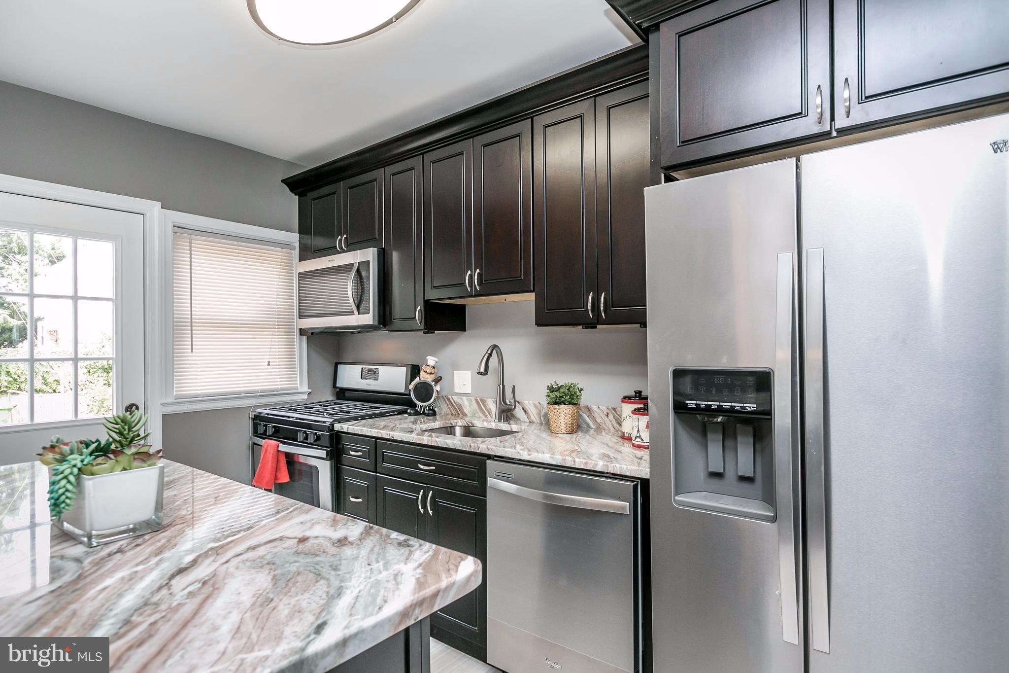 4674 Marble Hall Road Baltimore, MD 21239 - Photo 1 of 29 a kitchen with stainless steel appliances granite countertop a refrigerator a stove a sink dishwasher and microwave with wooden cabinets