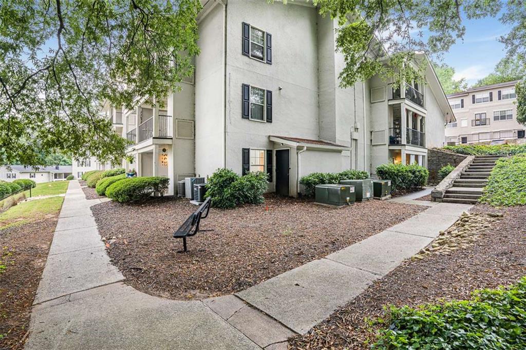 1150 Collier Road Northwest, Unit 25D Atlanta, GA 30318 - Photo 2 of 21 a view of a white house with a yard plants and large tree