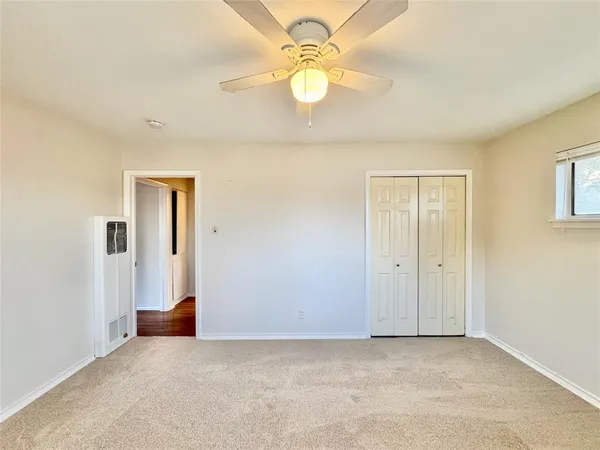 an empty room with chandelier fan and windows