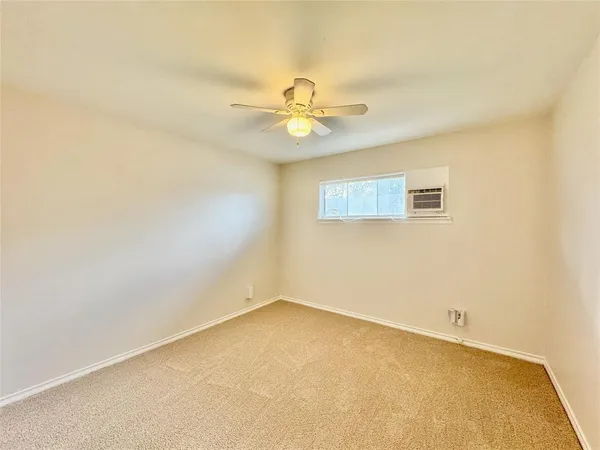 an empty room with a window and ceiling fan