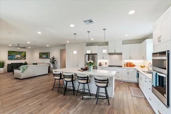 a kitchen with stainless steel appliances a dining table chairs microwave and stove top oven