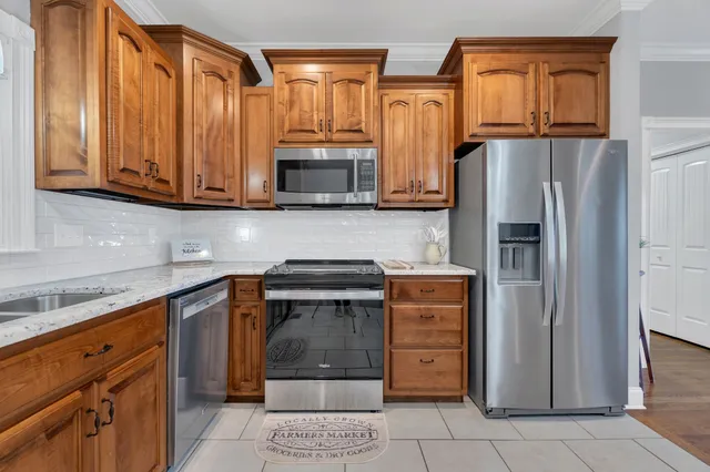 a kitchen with stainless steel appliances granite countertop a refrigerator and a stove top oven