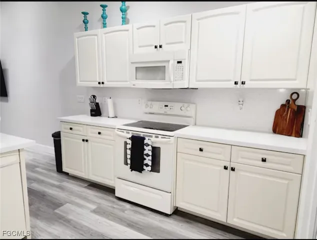 a kitchen with white cabinets and white appliances