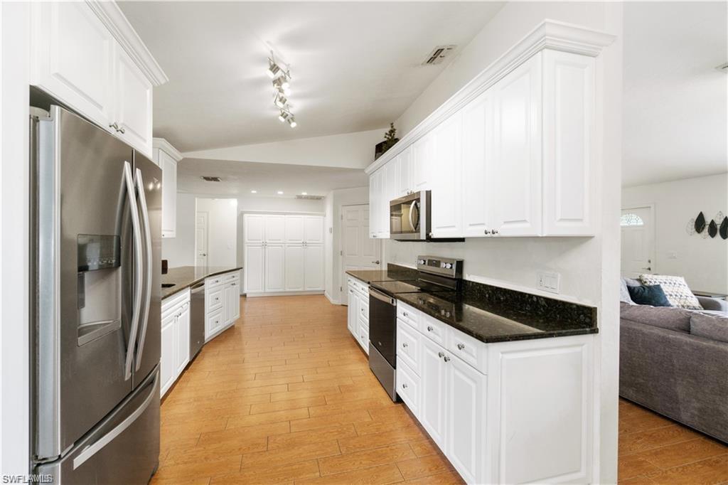 Undisclosed Address Naples, FL 34110 - Photo 5 of 19 a large white kitchen with granite countertop a refrigerator a sink dishwasher a stove and white cabinets with wooden floor