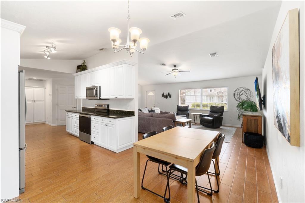Undisclosed Address Naples, FL 34110 - Photo 6 of 19 a open kitchen with stainless steel appliances kitchen island granite countertop a stove a sink dishwasher a dining table and chairs with wooden floor
