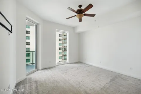 an empty room with windows and ceiling fan