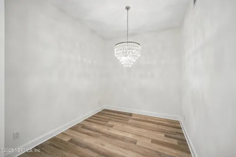 a view of a room with a chandelier fan and wooden floor