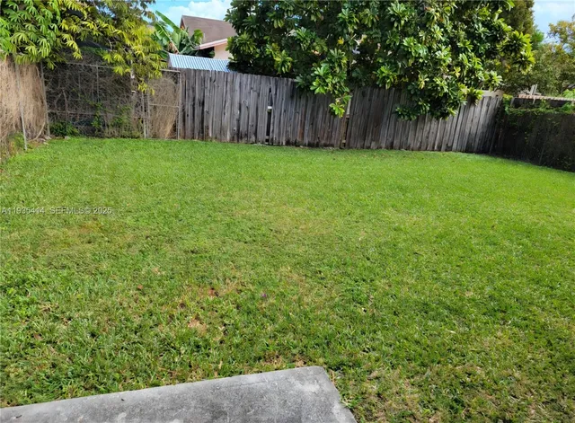 a view of backyard with wooden fence