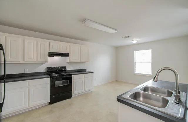 a kitchen with granite countertop a sink stainless steel appliances and cabinets