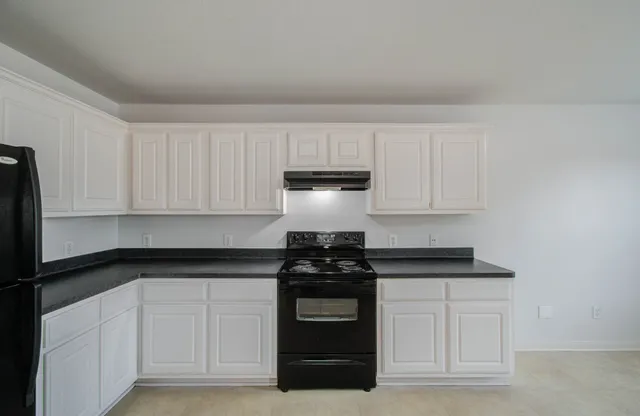 a kitchen with white cabinets and black appliances