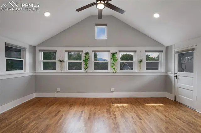 a view of an empty room with wooden floor and a window