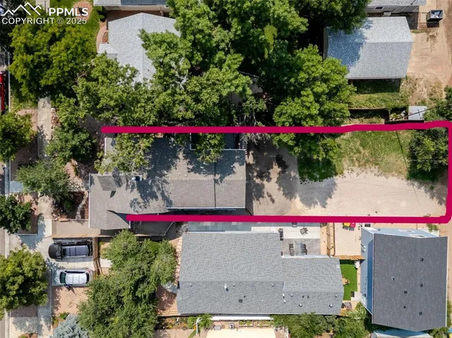 a view of backyard with table and chairs potted plants and large tree