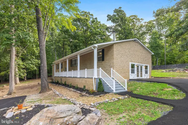a view of a house with backyard and trees in the background
