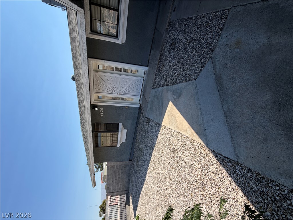 2820 South Sandhill Road, Unit A Las Vegas, NV 89121 - Photo 3 of 26 A welcoming entry with a white door and contrasting gray stucco, surrounded by a gravel and concrete path.
