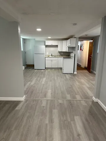 a view of a electric appliances in kitchen and empty room with wooden floor