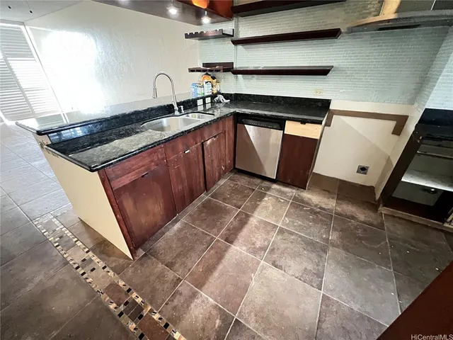 a kitchen with granite countertop a sink a stove and cabinets