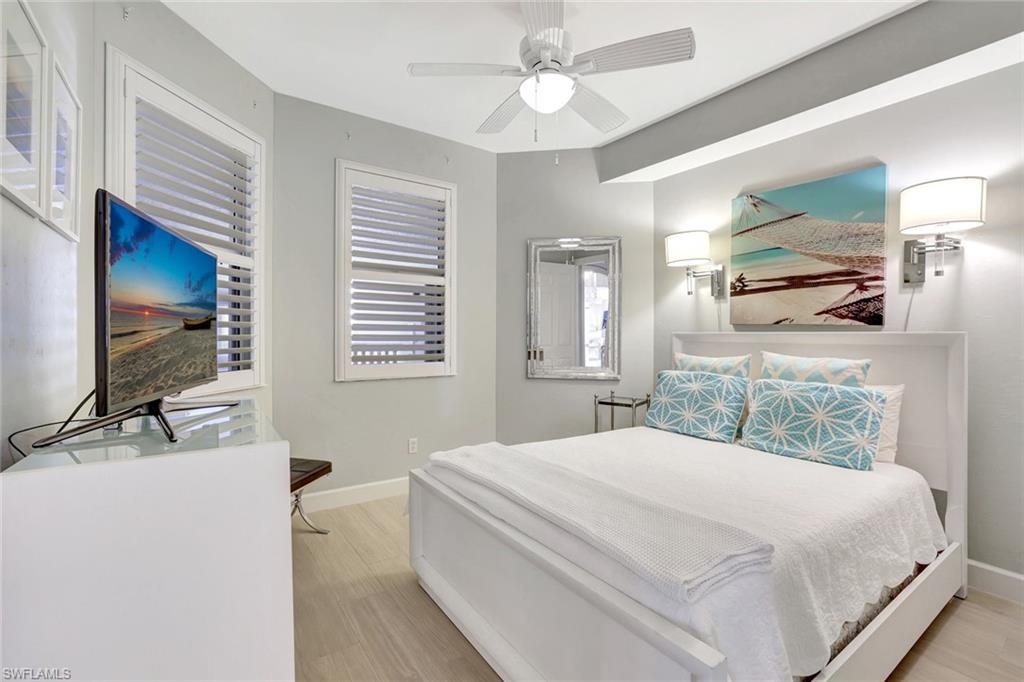 400 Flagship Drive, Unit 602 Naples, FL 34108 - Photo 18 of 37 a bedroom with a large bed and a flat tv screen on dresser