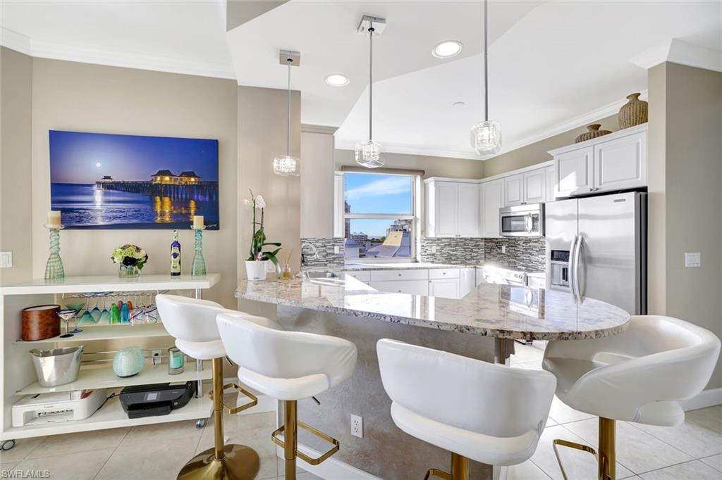 400 Flagship Drive, Unit 602 Naples, FL 34108 - Photo 6 of 37 a kitchen with kitchen island granite countertop a sink cabinets and stainless steel appliances