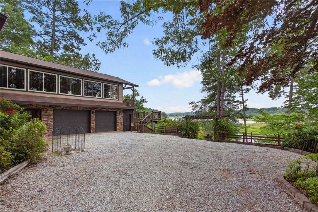 351 River Road Westminster, SC 29693 - Photo 44 of 50 A spacious gravel driveway leads to a charming residence, framed by mature trees and offering serene Lake Hartwell views.