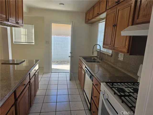 a kitchen with granite countertop a sink a stove and refrigerator