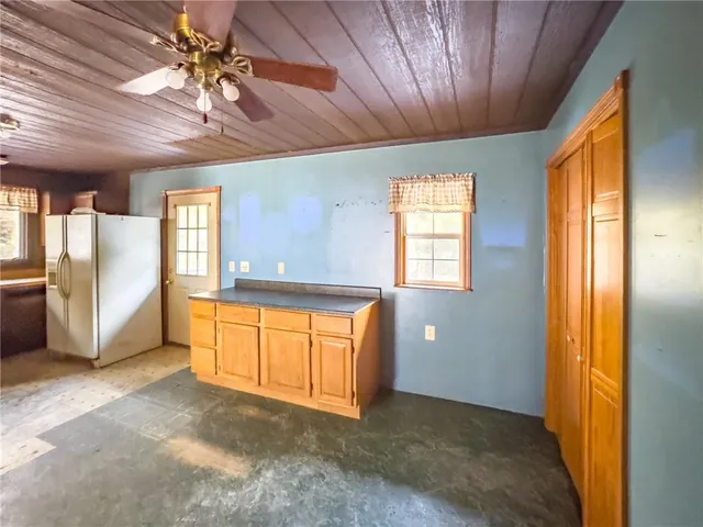 a view of an empty room with window and a kitchen
