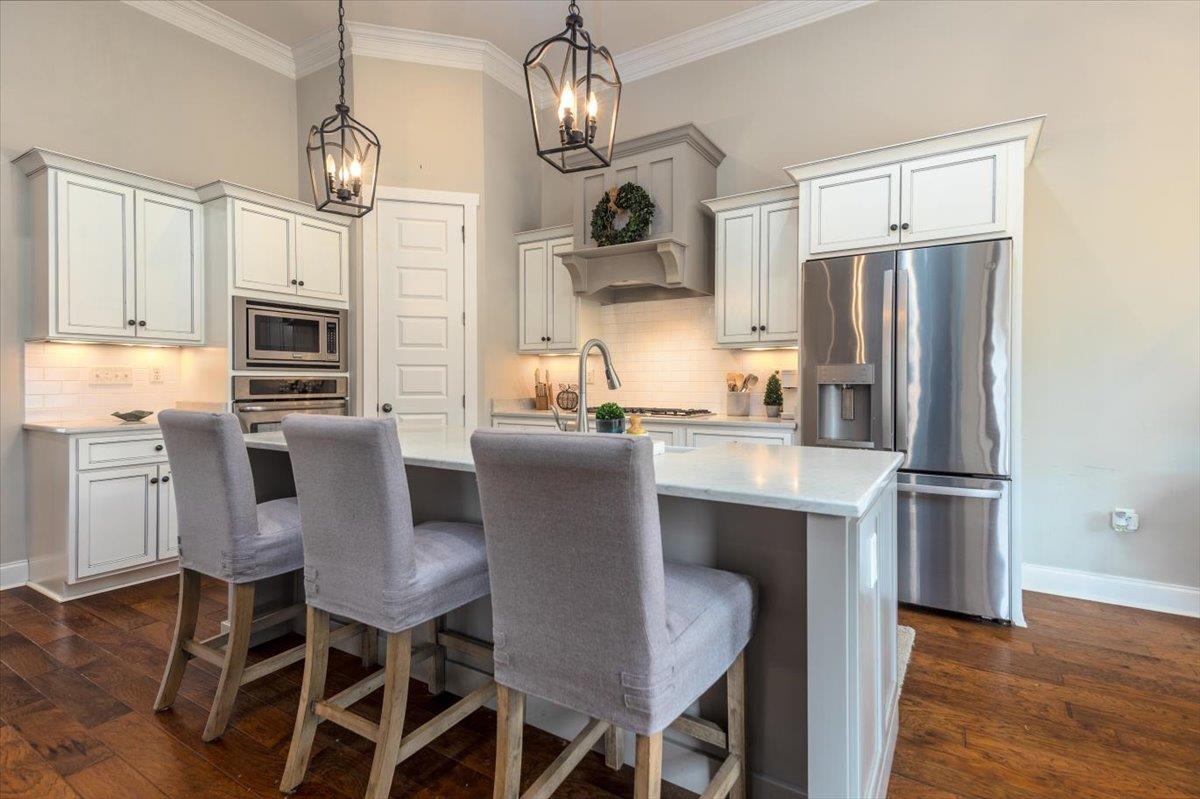 608 Cypress Run Cove Collierville, TN 38017 - Photo 13 of 40 Kitchen featuring stainless steel appliances, an island with sink, white cabinets, light stone counters, and dark wood-style floors