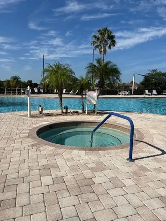 a view of a swimming pool with a table and chairs under palm trees