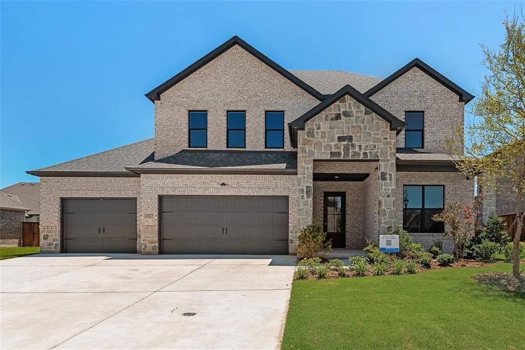 View of front of home with brick siding, driveway, a front yard, and stone siding