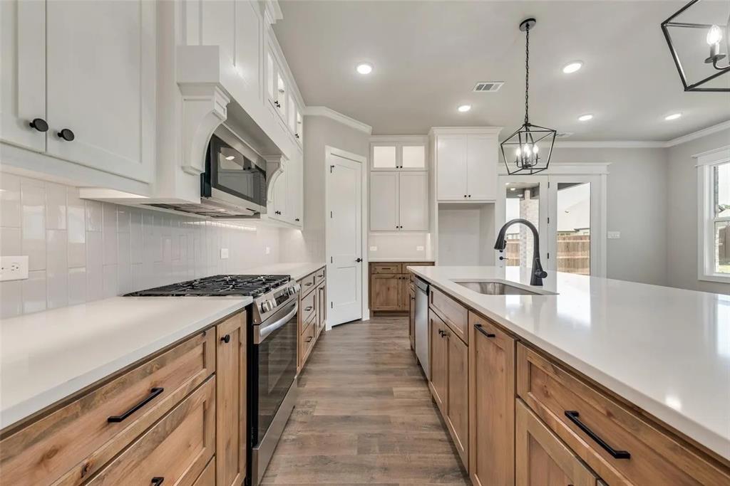 1327 Selby Road Van Alstyne, TX 75495 - Photo 5 of 32 Kitchen with stainless steel appliances, dual tone cabinets, dark wood-style flooring, ornamental molding, and tasteful backsplash