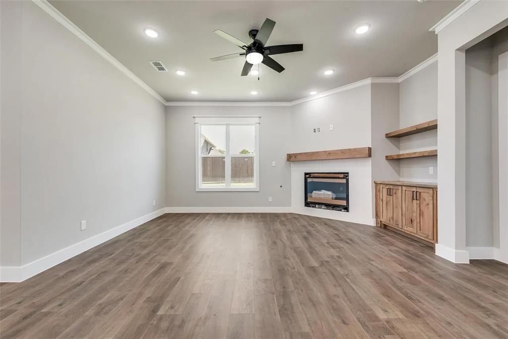 1327 Selby Road Van Alstyne, TX 75495 - Photo 7 of 32 Unfurnished living room featuring a ceiling fan, recessed lighting, crown molding, dark wood-style floors, and a glass covered fireplace