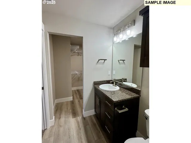 a bathroom with a granite countertop sink a mirror and a toilet