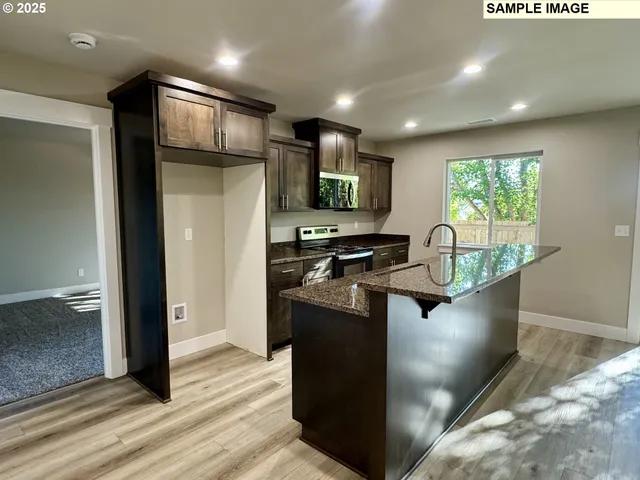 a kitchen with stainless steel appliances granite countertop a refrigerator a sink and a stove