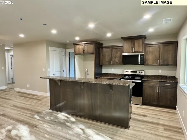 a kitchen with stainless steel appliances granite countertop a stove a sink and a microwave